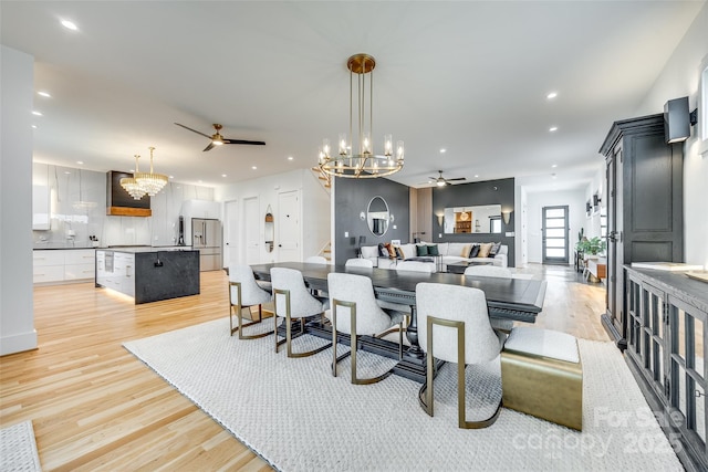 dining space with light wood-type flooring, ceiling fan with notable chandelier, and recessed lighting