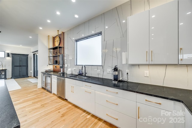 kitchen with light wood-type flooring, white cabinets, dishwasher, a sink, and beverage cooler