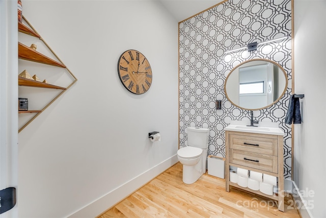 half bath featuring toilet, wood finished floors, vanity, and baseboards
