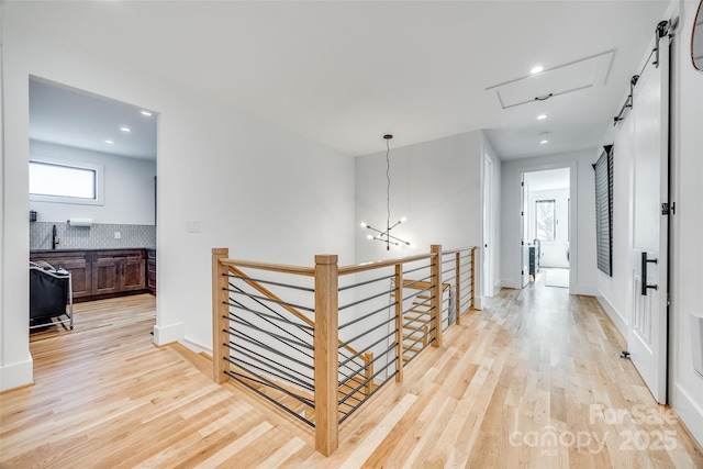 hallway with baseboards, an upstairs landing, and light wood finished floors