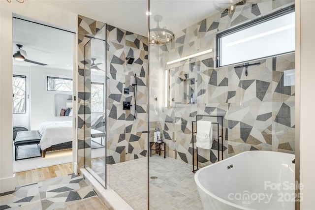 ensuite bathroom featuring ensuite bathroom, a shower stall, a freestanding bath, and an inviting chandelier