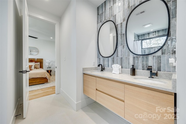 ensuite bathroom with connected bathroom, visible vents, a sink, tile walls, and double vanity