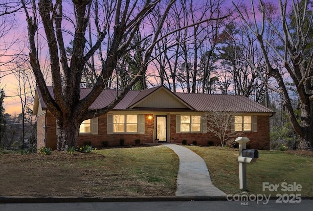 single story home featuring brick siding, metal roof, and a front lawn