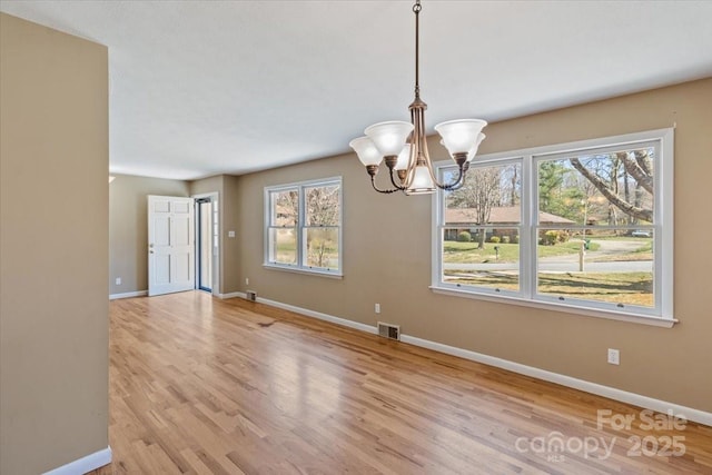 unfurnished dining area featuring visible vents, baseboards, and an inviting chandelier