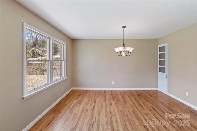unfurnished room with baseboards, light wood-style floors, and a chandelier