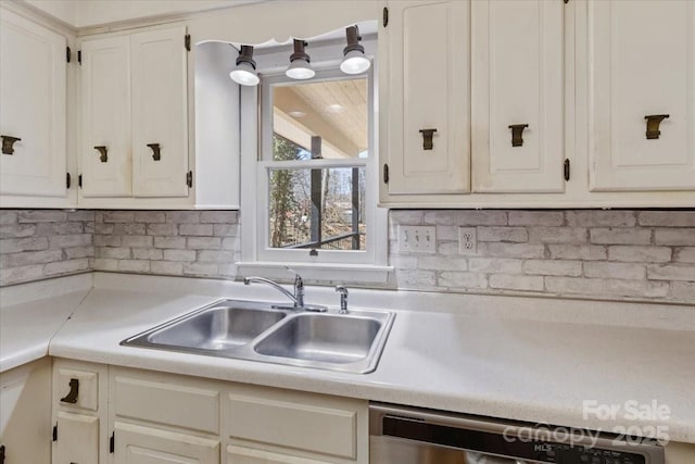 kitchen with stainless steel dishwasher, light countertops, white cabinetry, and a sink
