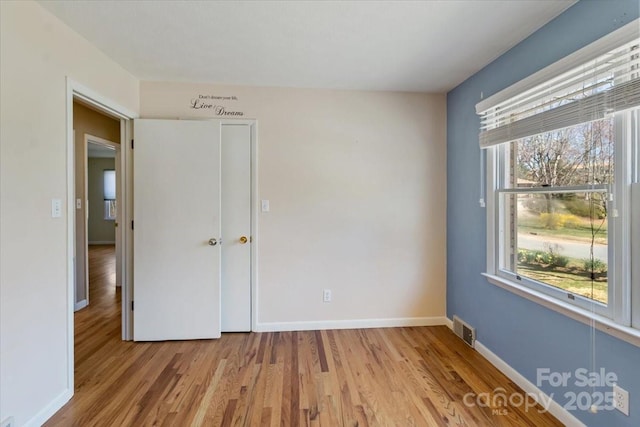 unfurnished bedroom featuring light wood finished floors, visible vents, and baseboards