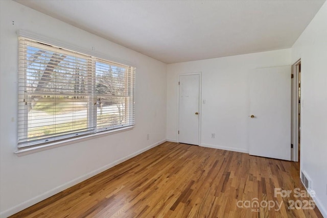unfurnished bedroom with visible vents, baseboards, and wood finished floors