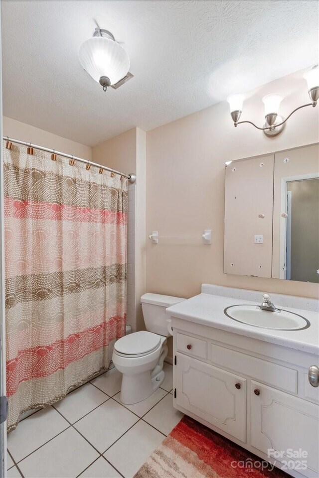 bathroom featuring tile patterned flooring, toilet, a shower with shower curtain, vanity, and a textured ceiling