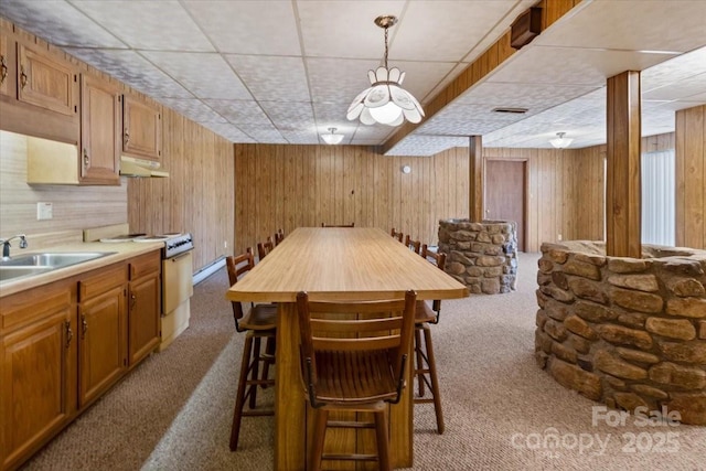 dining room with wooden walls, carpet flooring, and a drop ceiling