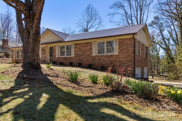 single story home featuring metal roof, brick siding, and an attached garage