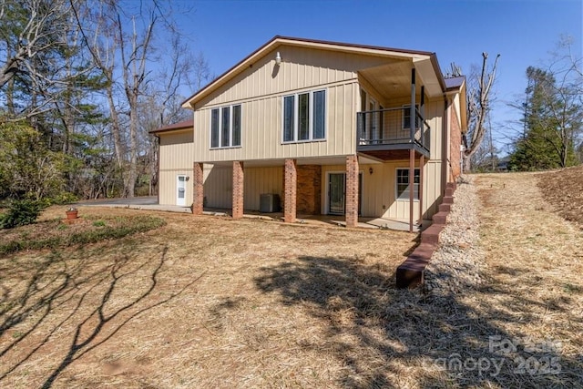 back of property featuring brick siding, central AC, and a balcony