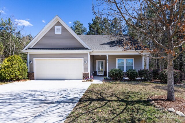 view of front of house featuring concrete driveway, roof with shingles, a front yard, brick siding, and a garage