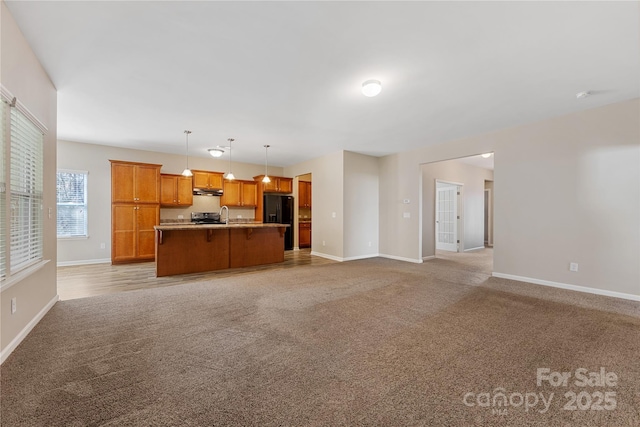 unfurnished living room featuring a sink, baseboards, and light colored carpet