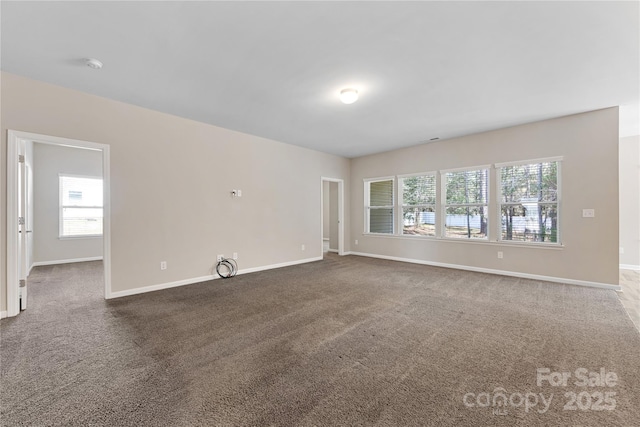 unfurnished living room with carpet flooring, baseboards, and a wealth of natural light