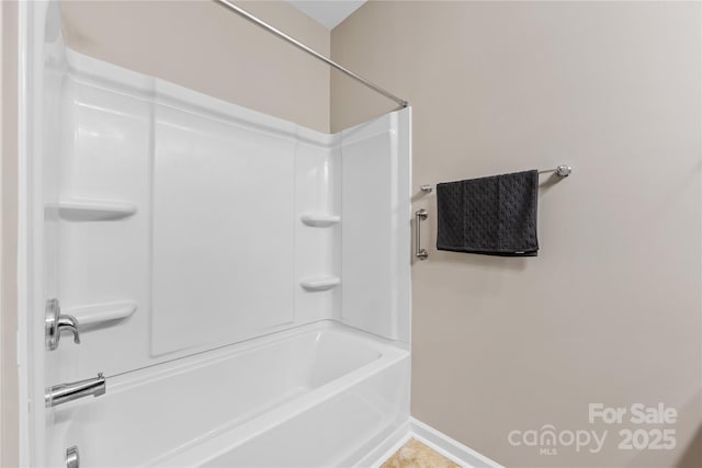 bathroom with washtub / shower combination and baseboards