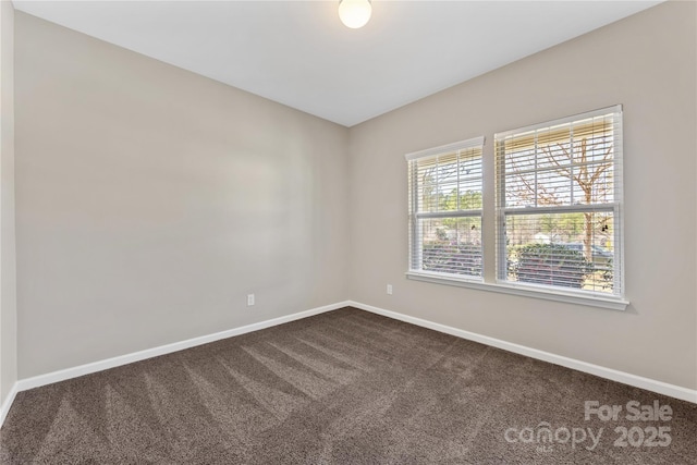 spare room featuring dark carpet and baseboards