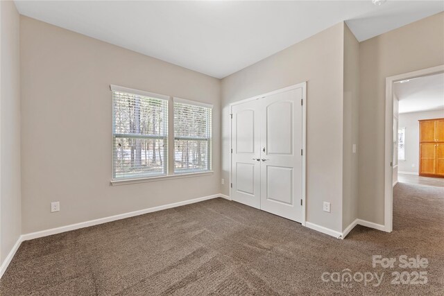 unfurnished bedroom with a closet, baseboards, and carpet floors
