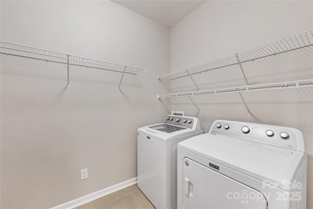 laundry area featuring washer and clothes dryer, light tile patterned floors, laundry area, and baseboards