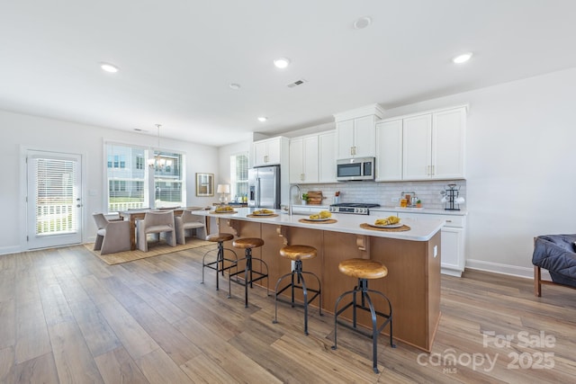 kitchen featuring tasteful backsplash, visible vents, light countertops, appliances with stainless steel finishes, and a sink