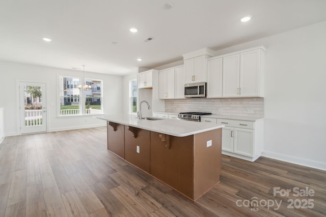 kitchen featuring dark wood-style flooring, tasteful backsplash, appliances with stainless steel finishes, and a sink