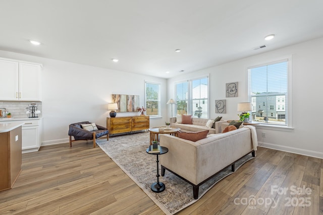 living room with recessed lighting, baseboards, visible vents, and light wood finished floors