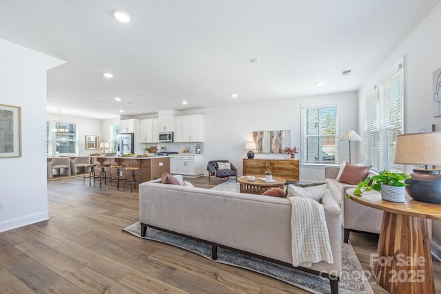 living room featuring recessed lighting, wood finished floors, visible vents, and a healthy amount of sunlight