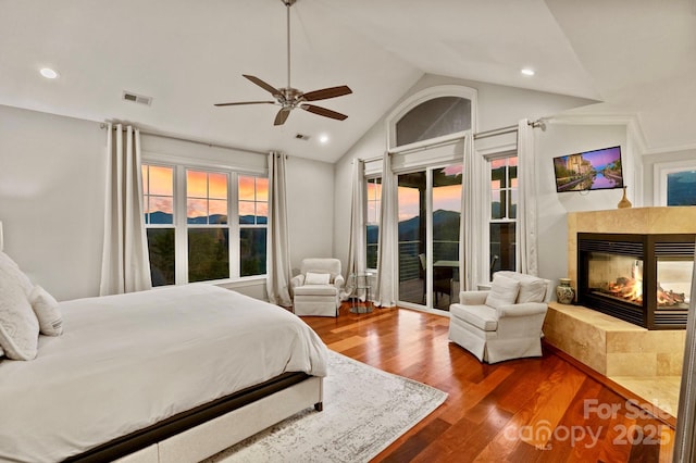 bedroom featuring visible vents, dark wood-type flooring, access to outside, a fireplace, and lofted ceiling