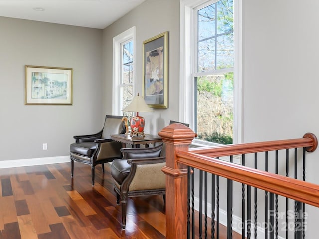 sitting room featuring an upstairs landing, baseboards, and wood finished floors