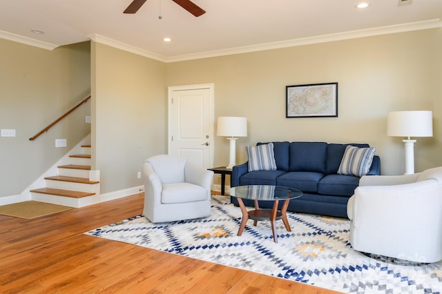 living area with ornamental molding, stairs, a ceiling fan, and wood finished floors
