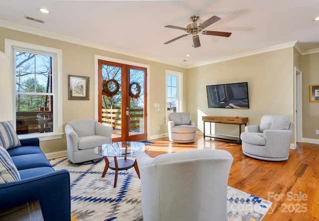 living area with crown molding, wood finished floors, visible vents, and a wealth of natural light