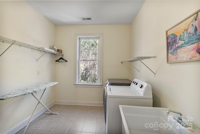 laundry area featuring visible vents, washer and clothes dryer, a sink, baseboards, and laundry area