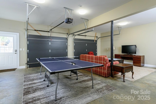 rec room with baseboards, concrete floors, and a garage