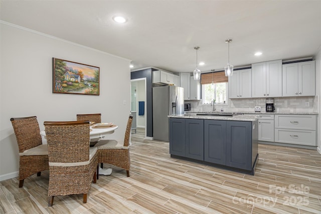 kitchen with stainless steel fridge with ice dispenser, baseboards, light wood-style flooring, a center island, and crown molding