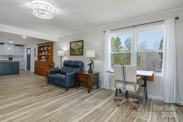 sitting room featuring light wood-style floors, crown molding, and baseboards