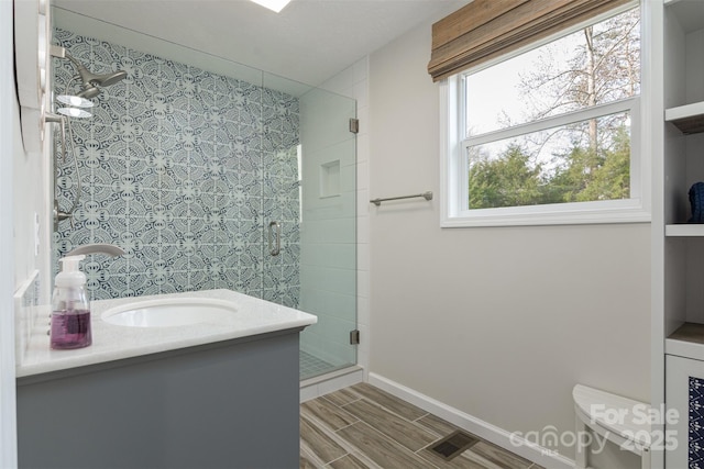 bathroom with visible vents, baseboards, toilet, a shower stall, and vanity