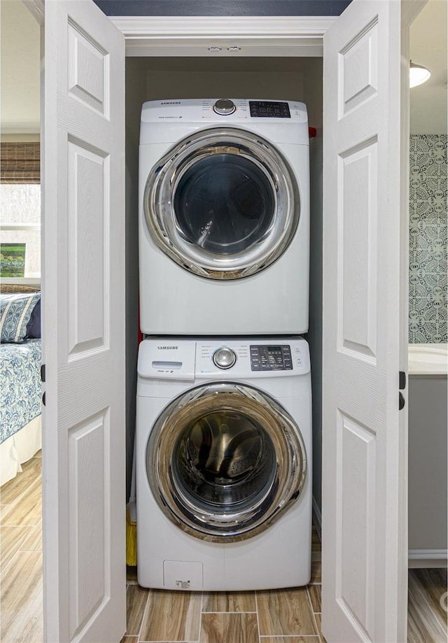 washroom featuring laundry area, wood finished floors, and stacked washer and clothes dryer
