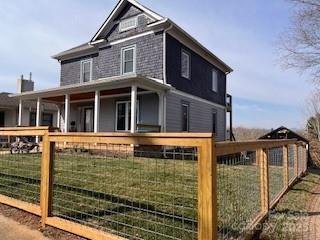 exterior space featuring a front lawn, covered porch, and a fenced front yard