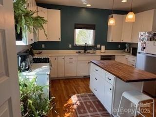 kitchen with a sink, white cabinetry, a center island, and freestanding refrigerator