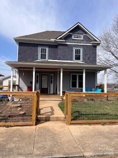 view of front of house with a fenced front yard, a porch, and a gate