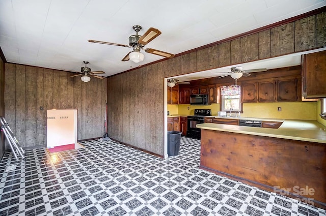 kitchen with wood walls, black appliances, light countertops, and ceiling fan