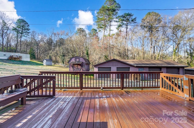 wooden deck with an outbuilding, a storage unit, and a garage