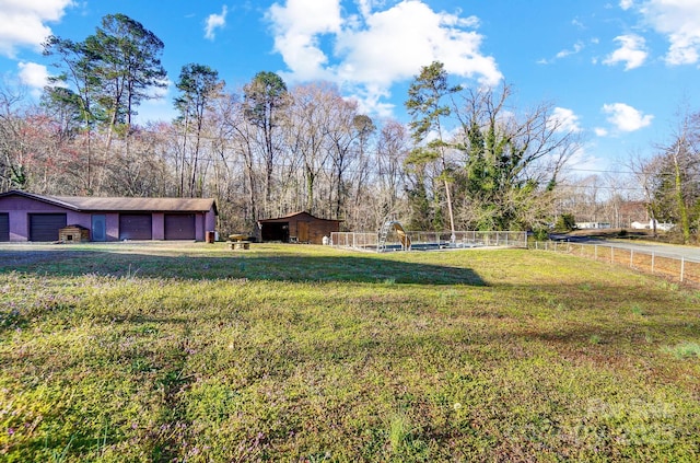 view of yard featuring an outdoor structure, fence, and a garage