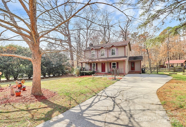 view of front of property with brick siding, a porch, concrete driveway, a front yard, and a chimney