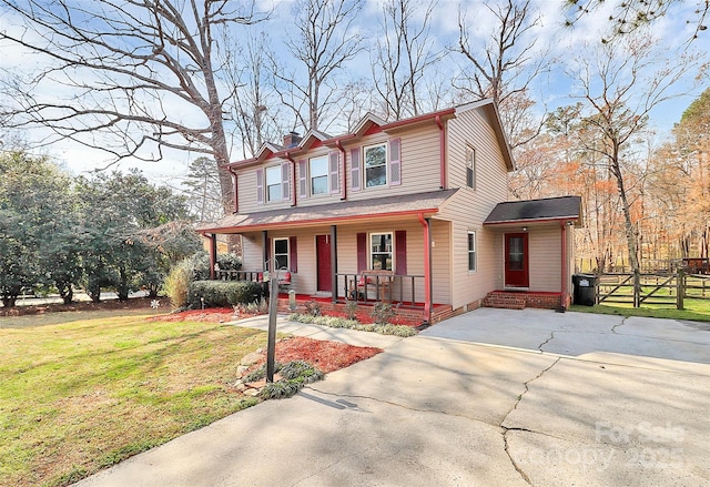 view of front of home featuring covered porch, concrete driveway, a front lawn, and fence