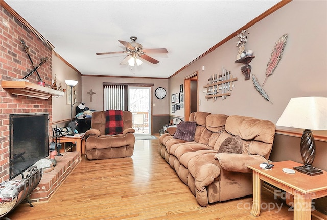 living area with wood finished floors, crown molding, a brick fireplace, and a ceiling fan