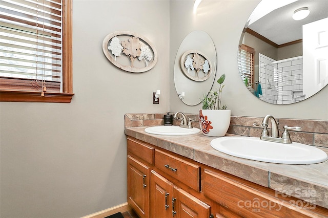 bathroom featuring double vanity, ornamental molding, baseboards, and a sink