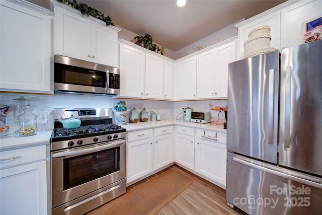 kitchen featuring backsplash, white cabinets, stainless steel appliances, and light countertops