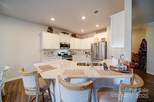 kitchen featuring a sink, dark wood-type flooring, appliances with stainless steel finishes, and a peninsula
