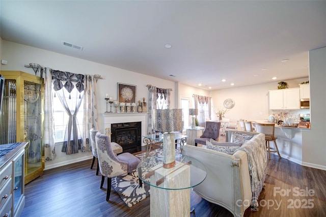 living room with a glass covered fireplace, recessed lighting, wood finished floors, and visible vents